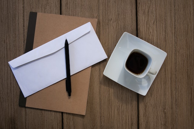  a cup of coffee next to an envelope on a notebook